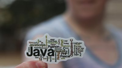 person in gray shirt holding a small paper with texts