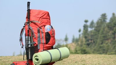 selective focus photo of red hiking backpack on green grass