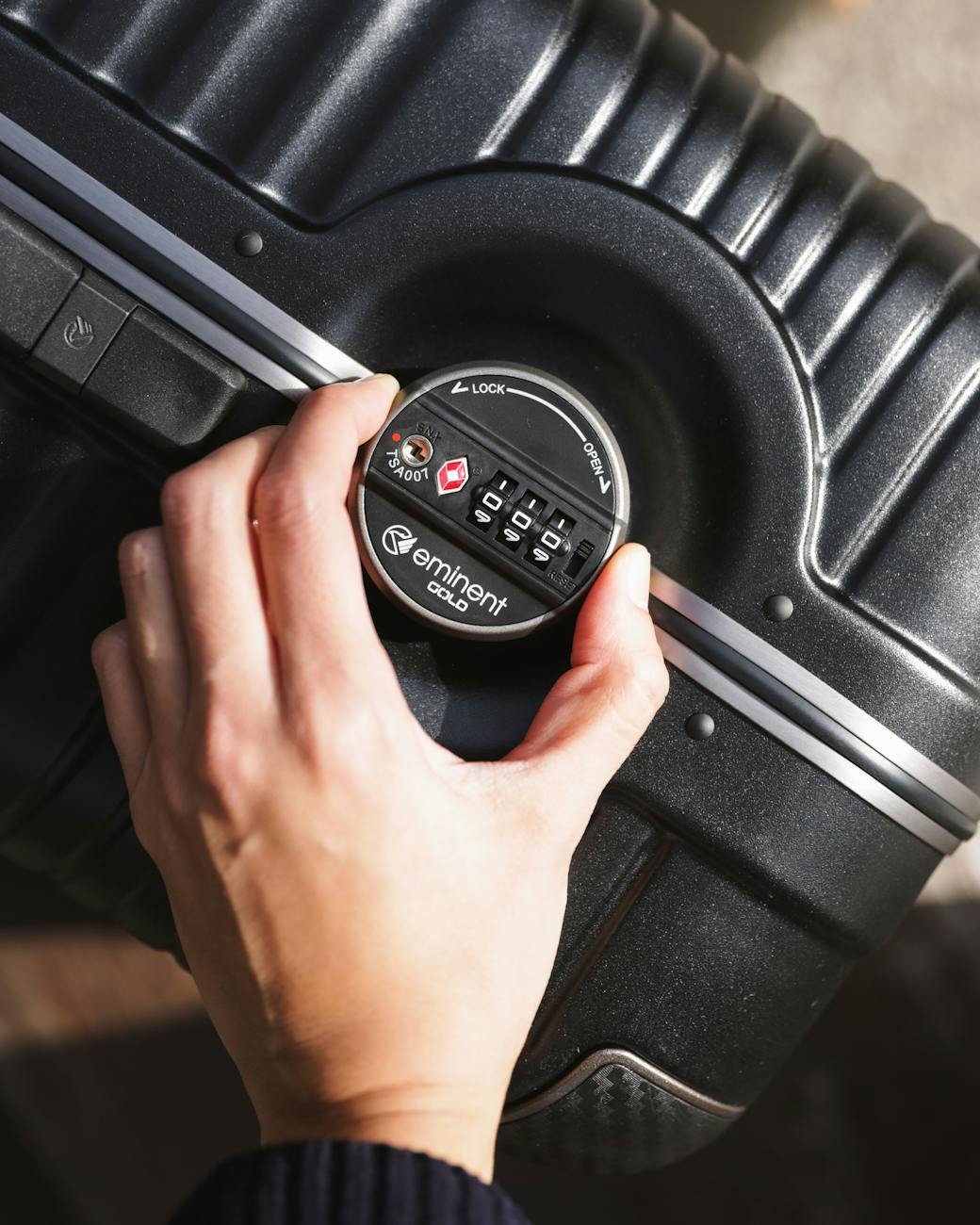 person hand holding knob of suitcase lock
