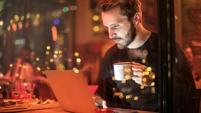 man holding mug in front of laptop