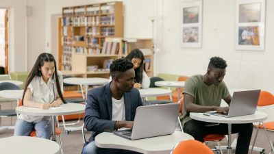 a pair of students looking at a man i front using a laptop